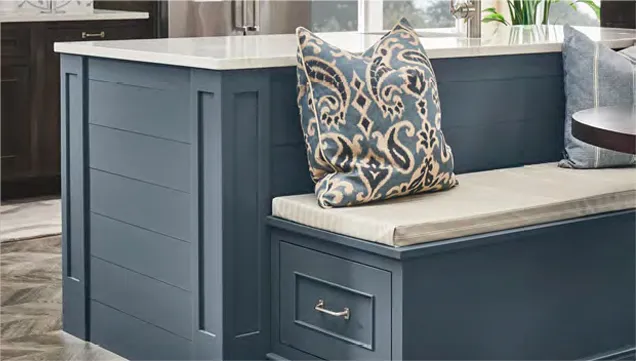 Stylish kitchen island with bench and sink, complete with a patterned pillow for added charm.